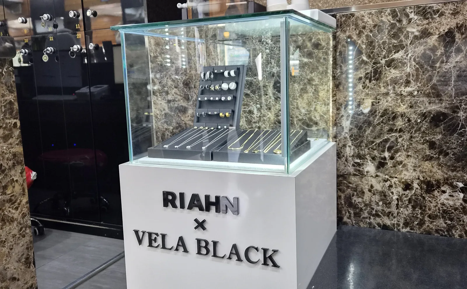 대리석 벽과 거울 사이에 놓인 VELA BLACK 진열장
